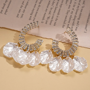 Détail macro de boucles d'oreilles en C avec zircons et glands en nacre sur métal doré