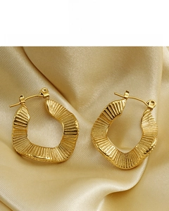 Macro shot of 18K gold plated hoop earrings with irregular wave texture on satin
