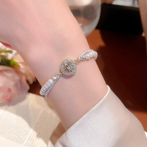 Nahaufnahme eines eleganten doppellagigen Armbands mit weißen Perlen und Sternanhänger