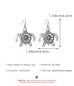 Detail view of silver turtle earrings with turquoise bead and ethnic patterns