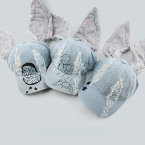 Detail einer Distressed-Denim-Basecap mit Plüsch-Hasenohren und Graffiti-Print-Mustern