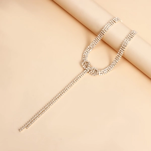 Macro shot of gold bowknot choker with dangling rhinestone tassels on a beige background