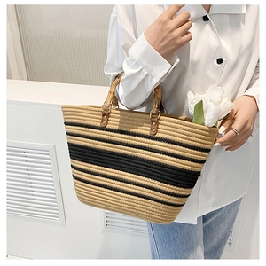 Detailed shot of the woven tote bag featuring a natural bamboo handle and stripe pattern