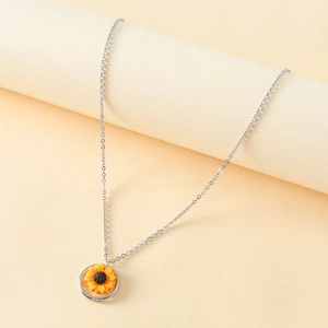 Silver stainless steel necklace with a yellow sunflower pendant on a beige display stand