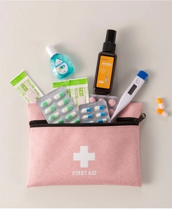 Pink portable first aid pouch with cross logo showing internal medicine storage space