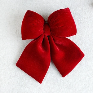 Large red velvet bow decoration for Christmas tree hanging on white fabric background