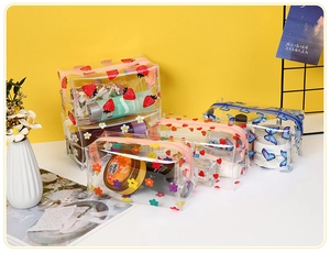 Detail of transparent PVC toiletry bags with floral and strawberry prints on yellow background