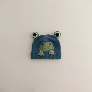 Close-up of blue ribbed knit baby hat featuring 3D frog patch with Good embroidery