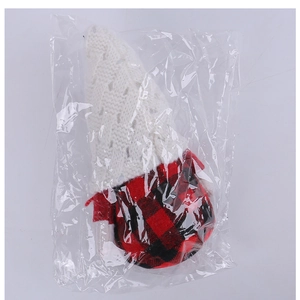 Detail of a Christmas gnome doll with red plaid body and white knit hat in packaging