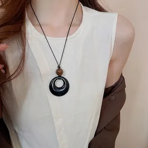 Ethnische Kunstlederkette mit schwarzem Ringanhänger und brauner Perle am Modell