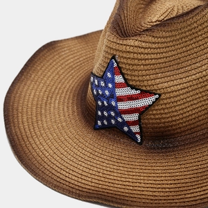 Close-up of brown straw cowboy hat featuring a sequined American flag star emblem