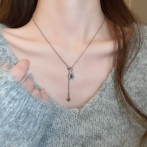 Détail du collier à pendentif soleil argenté avec œil de tigre porté au cou