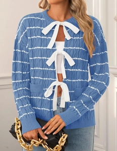 Detail of blue knit cardigan with white bow tie-up closure and wave textured pattern
