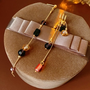 Detail of long tassel earrings with colorful glass beads on a brown velvet jewelry box