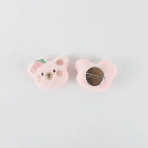 Detail of pink plush bear brooches with strawberry embroidery and metal pin backings