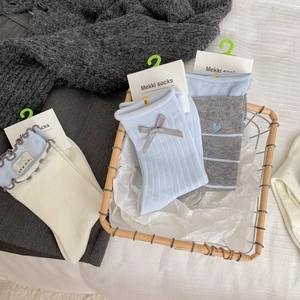 Gros plan de chaussettes en coton pastel avec nœud et broderie cœur dans un panier