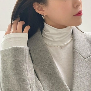 Close-up of pearl necklace and silver hoop earrings on a model in professional attire