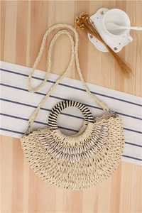 Detail of semi-circular straw bag with natural shells on wooden table with coffee cup