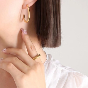 Polished gold C-shaped earrings and chunky twisted textured ring worn by model