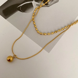 Detail view of 18K gold plated double-layered necklace with round bead and textured chain