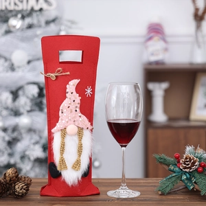 Detail of red felt Christmas gnome wine bottle cover with pink sequin hat and white faux fur