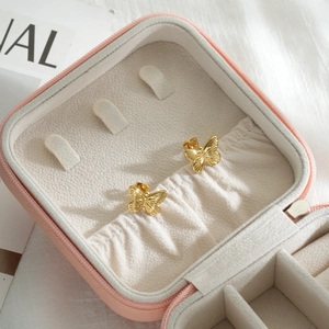 Golden butterfly stud earrings in a pink portable jewelry box for elegant organization