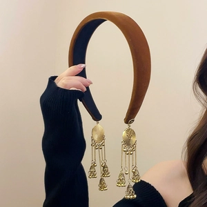 Close-up of brown velvet headband featuring dangling golden ethnic Jhumka bell tassels