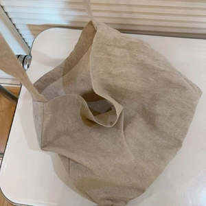 Detail view of large beige canvas tote bag showing textured natural fabric and wide strap