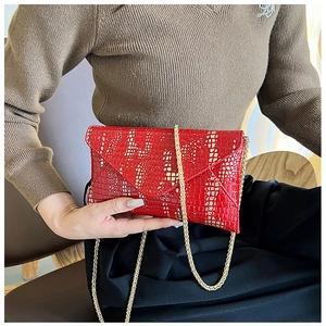 Detail of red crocodile pattern envelope bag with elegant golden chain strap