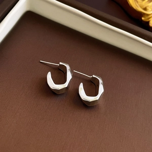 Detailed view of silver-tone irregular C-shape earrings with a polished metallic finish