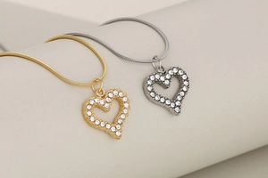 Close-up of gold and silver hollow heart pendants with crystals on sleek snake chains