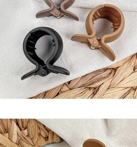 Flat lay of matte hair claw clips in black, brown, and beige on a woven mat