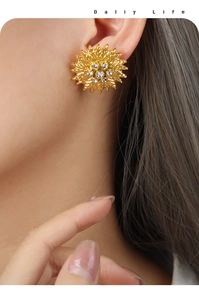 Detail of sunflower earrings in gold finish with sparkling cubic zirconia on a model