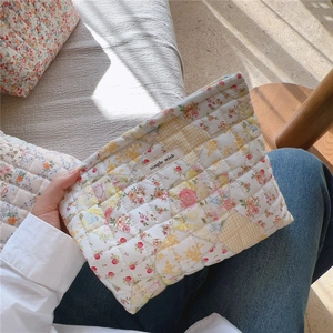 Pochette trapuntata a fiori tenuta in mano per mostrare morbidezza e dimensioni