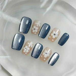 Faux ongles faits main œil de chat bleu avec relief floral blanc et strass scintillants