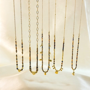 Bohemian necklaces with tiger eye beads and gold pendants on white silk background
