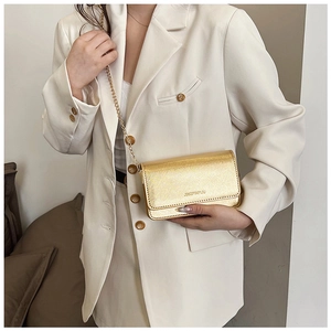 Detail of gold chain crossbody bag with fine texture and branded lettering flap