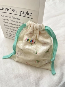 Détail de la pochette en velours à motif d'ours et fleurs avec cordons de serrage vert menthe