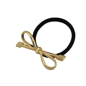 Detailed view of elastic black hair tie with a polished gold alloy bow charm accessory