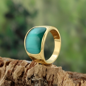 Golden stainless steel ring with green cat eye stone displayed on natural wood bark