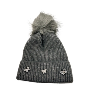 Detail of dark grey knit beanie featuring fluffy faux fur pompom and shiny butterfly crystals