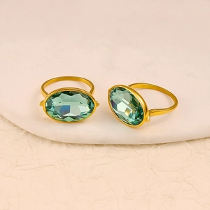 Elegant gold stainless steel rings featuring oval green sapphire stones on a stone base