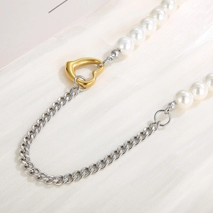Detail of Cuban chain mixed with faux pearls and golden heart clasp on fabric