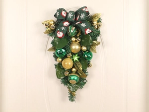 Detail of green teardrop Christmas door swag with red ribbons and festive gold ornaments