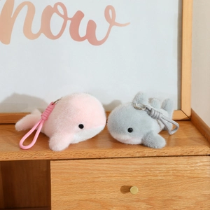 Close-up of plush whale keychains in pink and grey with soft faux rabbit fur texture