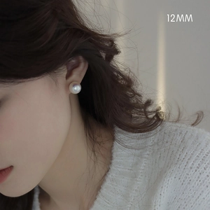 Detail of a 12mm white round pearl earring with soft luster worn by a model