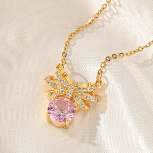 Macro shot of gold bow pendant necklace with pink round zircon and white pavé crystals