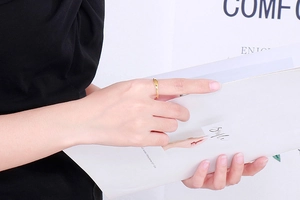 Minimalist golden titanium ring worn on index finger during daily lifestyle activities
