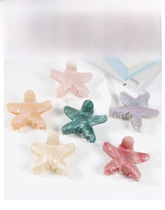 Dettaglio di pinze per capelli a forma di stella con trama marmorea in sei colori pastello