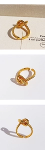 Close-up of gold plated twisted knot open ring with detailed rope texture and vintage style